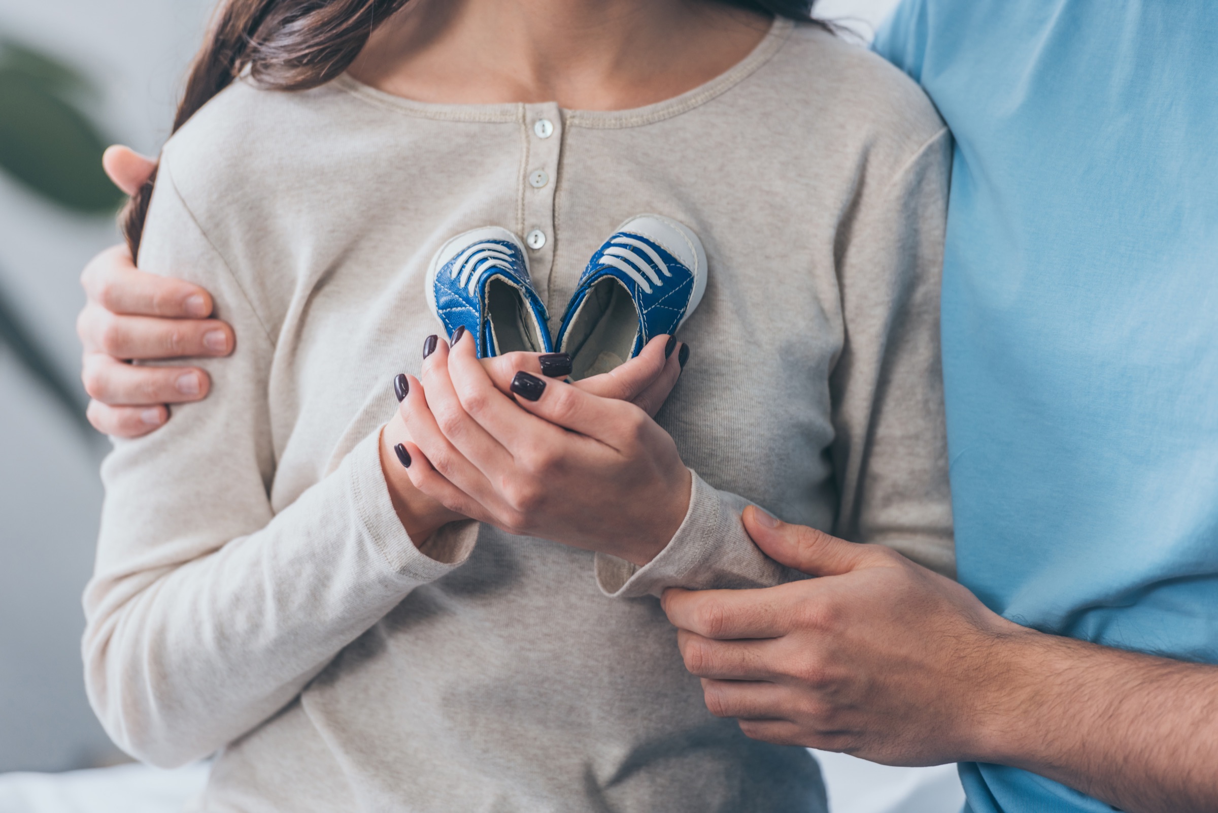 Trauernde Eltern mit den Schuhen ihres Sternenkindes